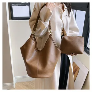 Close-up of brown textured leather tote bag and matching zipper pouch with gold rings