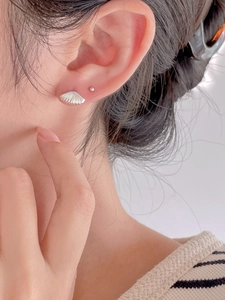 Close-up of S925 sterling silver shell earrings worn on ear with natural luster