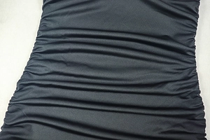 Detailed close-up of black ruched fabric texture on a slim fit bodycon midi dress