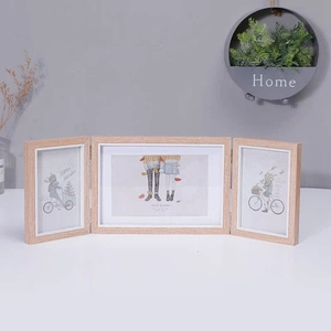 Detail of Nordic style triple folding wood photo frame with seasonal art on a white desk
