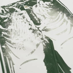 Detail of green and white abstract bone print trousers with textured twill fabric and button