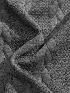 Detailed macro shot showing the dark gray jacquard texture and quilted pattern of the fabric