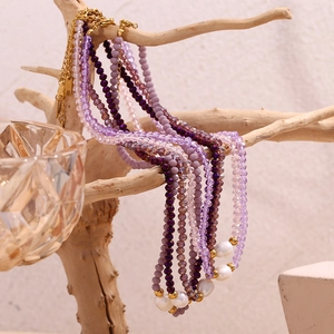 Purple crystal beads and freshwater pearl necklace with gold clasp on wooden branch