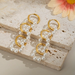 Detailed shot of interlocking gold rings and white imitation pearls on a textured stone
