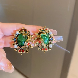 Detail view of vintage emerald crown earrings with gold metal lace and pearls