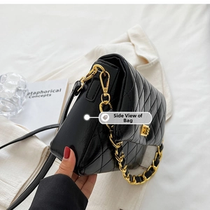 Detail of black quilted leather shoulder bag with gold chain strap on lifestyle background