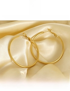 Macro shot of polished 18K gold plated titanium steel hoop earrings on satin
