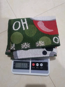 Christmas place mat weighing 66.5g on a scale, featuring green festive knitted fabric