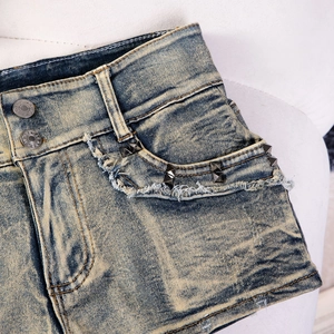 Nahaufnahme der Distressed-Denim-Shorts mit Vintage-Nieten und Doppelknopf-Verschluss
