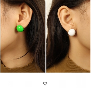 Close-up of minimalist half-sphere stud earrings in neon green and white finishes