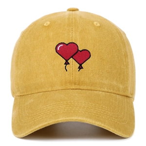 Macro detail of red heart embroidery on yellow washed cotton baseball cap texture
