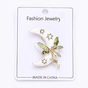 Detail view of crescent moon fairy brooch with white enamel, gold stars and green glitter
