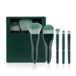 Detail view of 5 travel makeup brushes with green gradient bristles in a compact mirror case