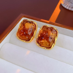 Close-up of geometric amber resin earrings with irregular gold metal wave frames
