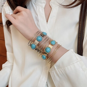 Detail shot of bohemian turquoise bangle set in gold and silver layered on arm