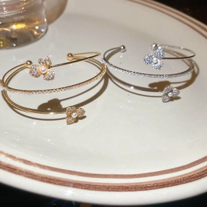 Detailed close-up of double-layer flower and pearl bracelets in gold and silver finish