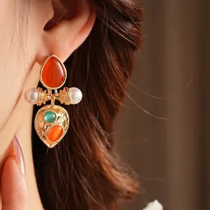 Vintage palace style gold earrings with cat eye stones and pearls on a female model