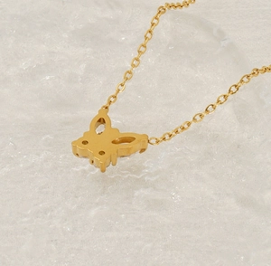 Detailed macro view of a gold butterfly pendant necklace with zircon stones on crystal ice