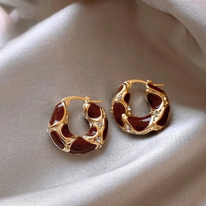 Golden geometric hoop earrings with dark red enamel and rhinestones on silk fabric
