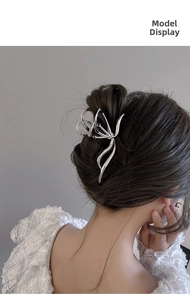 Detail of silver butterfly metal hair claw clip worn in an elegant French updo style