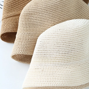 Dettaglio ravvicinato della trama dei cappelli in paglia intrecciata nei colori caffè e beige