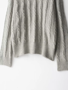 Detailed close-up of grey cable knit pattern and ribbed hem on cozy knit sweater
