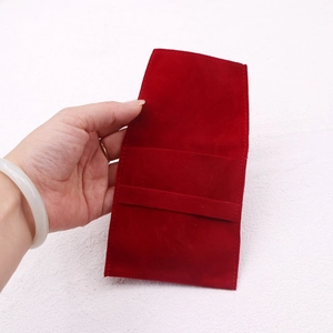 Deep red suede jewelry pouch held in hand to showcase its compact size and texture