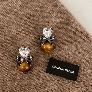Vintage heart zircon and tiger eye stone earrings with black bow on brown knit background