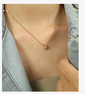 Détail du collier croissant de lune doré avec quatre perles blanches sur chaîne fine