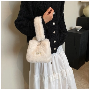 White faux fur bucket bag shown on a model in a cozy indoor setting with a soft knit outfit