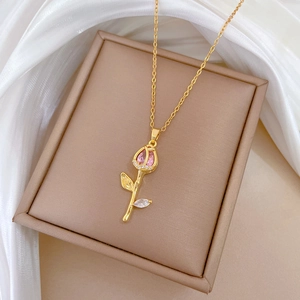 Detailed shot of golden tulip necklace with pink gemstone and zircons in a jewelry box