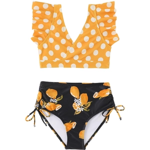 Dettaglio bikini da bambina con top giallo a pois e slip con stampa di limoni