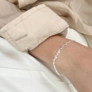 Close-up of minimalist S925 sterling silver twisted sequin bracelet on a wrist