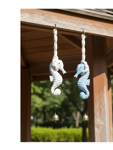 Detail of blue and white wooden seahorse ornaments with metal bells hanging outdoors