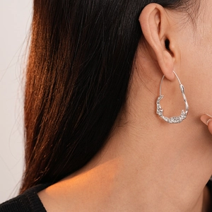 Detail of silver irregular liquid metal earrings with a wrinkled texture on model