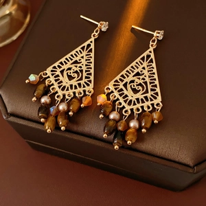 Detailed view of hollow triangle gold earrings with tiger eye beads on a jewelry box