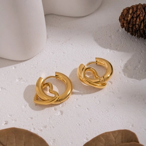 Detailed view of heart-shaped gold stainless steel earrings on a natural stone background