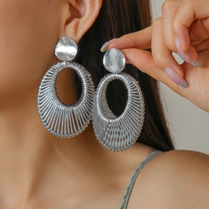 Fashionable woven velvet oval hoop earrings in silver metal shown on a model