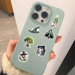 Hand holding forest witch stickers with cat and nature motifs on a green phone case