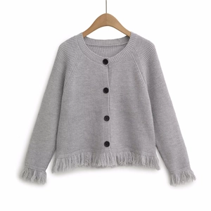 Grey knit cardigan with black buttons and fringe trim detail on a wooden hanger