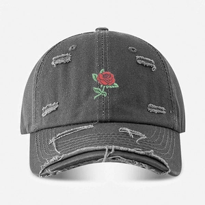 Detailed view of red rose embroidery and distressed rips on gray washed baseball cap