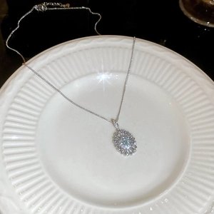 Macro view of oval light blue zircon pendant necklace on a white textured porcelain plate