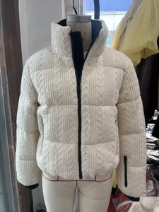 Detailed view of cream knit texture on ski jacket with black zipper and ribbed cuffs