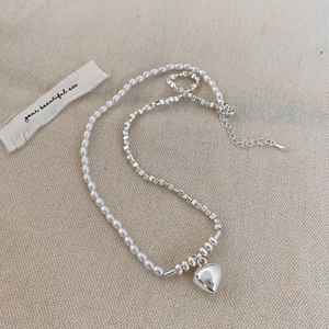 Detail shot of vintage faux pearl and silver bead jewelry set with a heart pendant