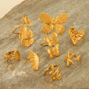 Detail of gold-plated rings set featuring butterfly and snake motifs on natural rock