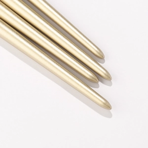 Detail of four champagne gold makeup brushes with a metallic finish and soft rounded tips