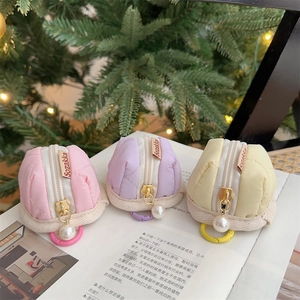Close-up of quilted headphone pouches in pink, purple, and yellow with pearl zippers