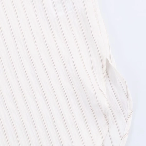Detail view of white and brown striped fabric featuring a curved hem and side slit design