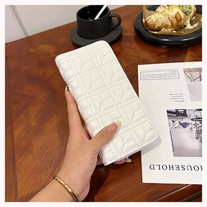 Close-up of a white quilted long wallet for women held in a casual cafe lifestyle setting