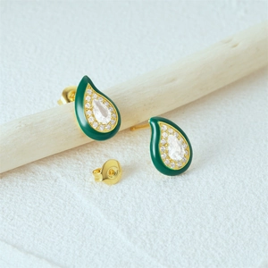 Macro shot of gold teardrop earrings with green enamel and sparkling crystals